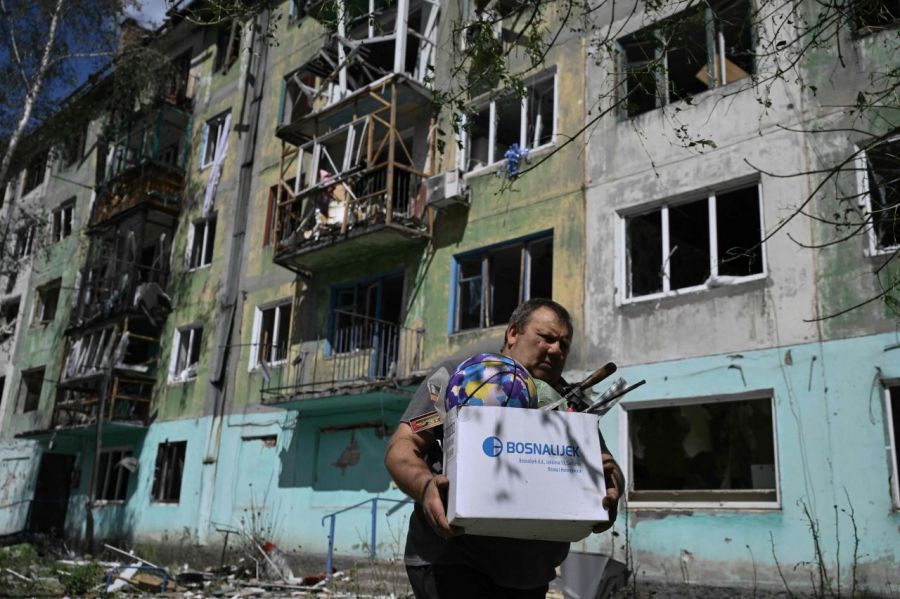 지난 12일(현지사간) 우크라이나 도네츠크 지역 빌로제르스케 마을에서 러시아의 공습 이후 한 주민이 파손된 건물에서 소지품을 들고 나오고 있다. AFP연합뉴스