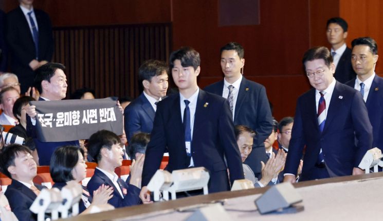 국민의힘 안철수 의원이 15일 서울 세종문화회관에서 열린 80주년 광복절 경축식에서 이재명 대통령이 경축사를 마치고 자리를 향할 때 '조국·윤미향 사면 반대'라는 문구가 적힌 펼침막을 들어보이고 있다. [대통령실통신사진기자단] 연합뉴스
