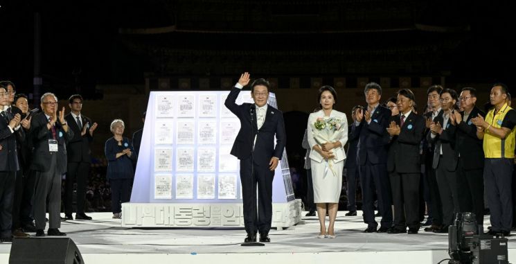 이재명 대통령과 김혜경 여사가 15일 서울 세종대로 광화문광장에서 열린 제21대 대통령 국민임명식 '광복 80년, 국민주권으로 미래를 세우다' 행사에서 '빛의 임명장' 큐브가 완성된 뒤 인사하고 있다. 연합뉴스