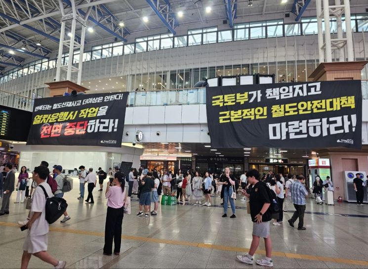 23일 서울역 내 역사에 걸린 '열차운행시 작업 전면 중단'과 '근본적인 철도안전대책 마련'을 촉구하는 현수막 아래에 승객들이 이동하고 있다. 철도노조 제공