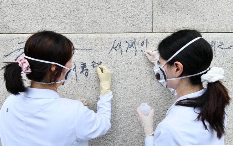 국립고궁박물관 유물과학과 관계자들이 지난 11일 서울 경복궁 광화문 석축에 남은 낙서를 제거하고 있다. 연합뉴스