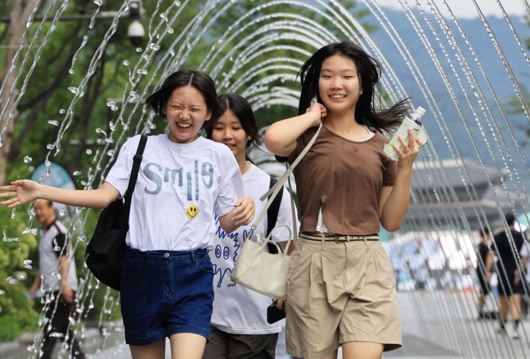 폭염이 이어진 24일 서울 광화문 광장에서 시민들이 분수 터널을 지나며 즐거워하고 있다. 연합뉴스