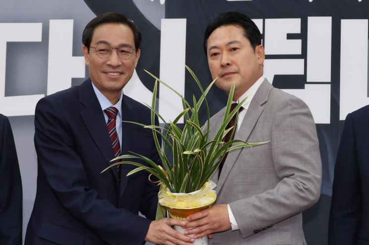 우상호 대통령실 정무수석(왼쪽)이 27일 서울 여의도 국회에서 국민의힘 장동혁 신임 대표를 예방해 이재명 대통령이 보낸 축하난을 전달하고 있다. 연합뉴스