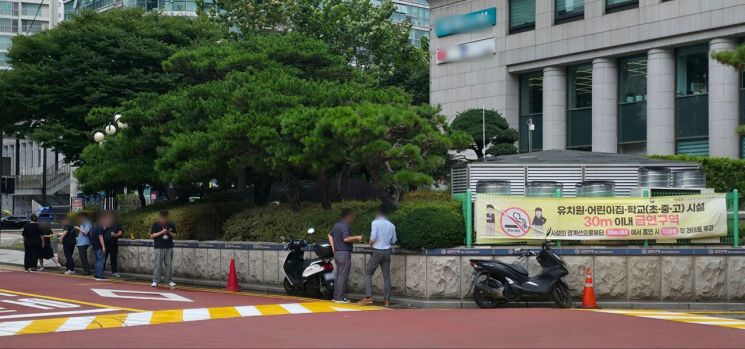 서울 마포구 공덕초등학교 앞에 걸려있는 30m 이내 금연구역 현수막 앞에서 직장인들이 담배를 피우고 있다. 최영찬 기자