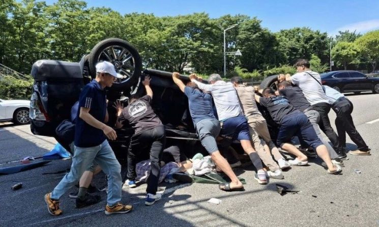 지난달 2일 오후 안산시 상록구 부곡동 육교 인근에서 주행하다가 사고가 뒤집힌 차량을 발견한 시민들이 힘을 합쳐 차량을 들어올리고 있다. 안산시