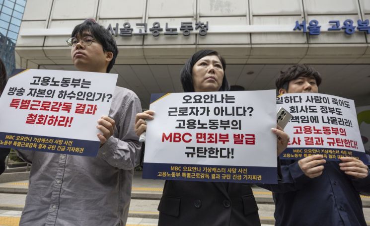 지난 5월 19일 서울 중구 서울고용노동청 앞에서 열린 MBC 기상캐스터였던 고(故) 오요안나씨 특별감독결과 규탄 기자회견에서 오씨의 어머니 장연미 씨(가운데)가 손팻말을 들고 있다. 연합뉴스