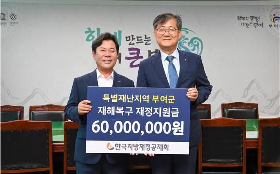 한국지방재정공제회 정선용 이사장(오른쪽)이 5일 부여군청에서 박정현 부여군수(왼쪽)에게 특별재난지역 호우 피해 복구를 위한 재정지원금 6000만원을 전달하고 있다. 한국지방재정공제회 제공