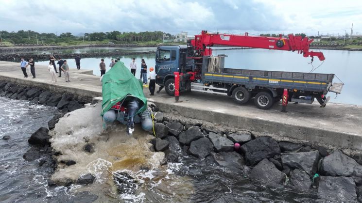 해경과 경찰 등 관계자들이 8일 오전 제주시 한경면 용수리 해안가에서 이날 오전 발견된 미확인 보트를 조사해 인양하려 하고 있다. 연합뉴스