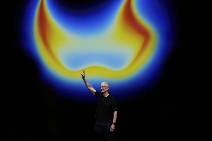 Apple CEO Tim Cook is waving to the audience on stage during the new product announcement. Photo by AP