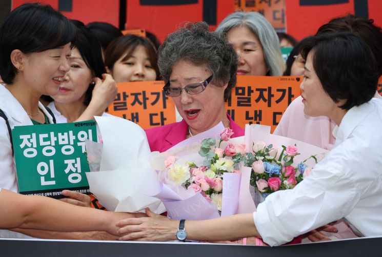 성폭행하려던 남성의 혀를 깨물어 중상해 혐의로 기소돼 유죄 판결을 받았던 최말자 씨가 10일 부산지법에서 열린 재심 선고 공판을 마친 뒤 꽃다발을 받고 있다. 최씨는 61년 만에 열린 재심에서 무죄를 선고받았다. 연합뉴스
