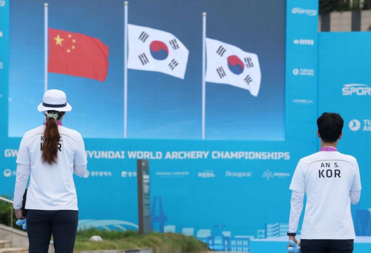 12일 광주 동구 국립아시아문화전당 5·18민주광장에서 열린 2025 세계양궁선수권대회 리커브 여자 개인전 시상식에서 강채영과 안산이 애국가가 나오자 태극기를 바라보고 있다. 연합뉴스