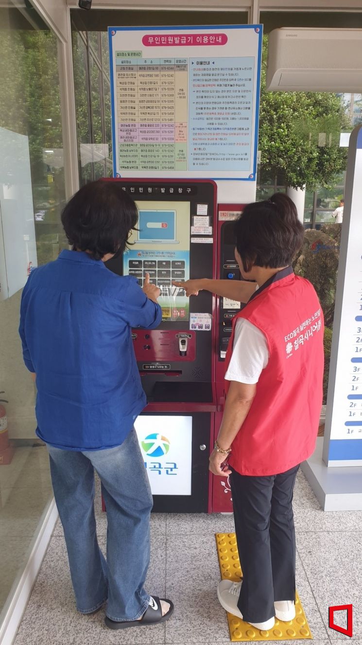 무인민원발급기 사용이 서툰 민원인의 옆에서 친절히 사용법을 알려주고 있다. 김이환 기자