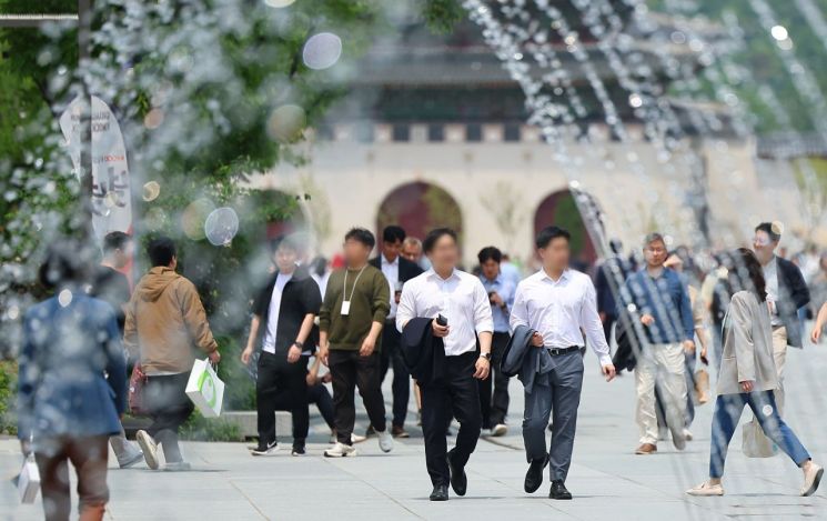 서울 광화문광장에서 직장인들이 외투를 팔에 걸고 산책을 즐기고 있다. 연합뉴스