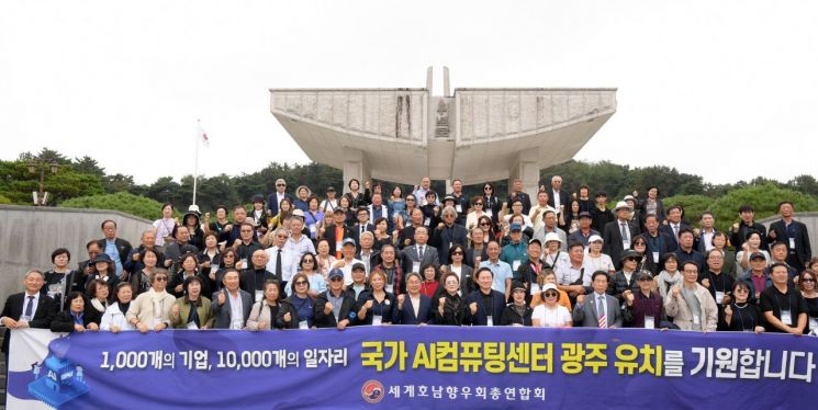 강기정 광주시장이 지난 4일 국립5·18민주묘지를 방문한 세계호남향우회 총연합회 회원들과 함께 '국가AI컴퓨팅센터 유치 기원' 플래카드를 들고 기념촬영을 하고 있다. 광주시 제공