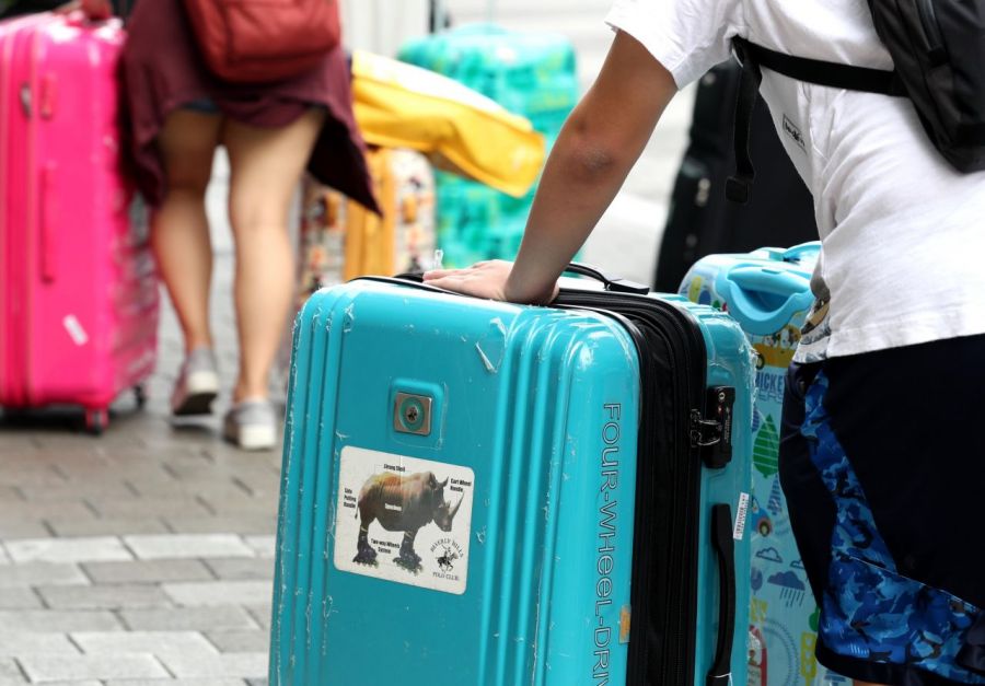 Tourists pulling their suitcases at the airport bus stop. Photo by Asia Economy Database