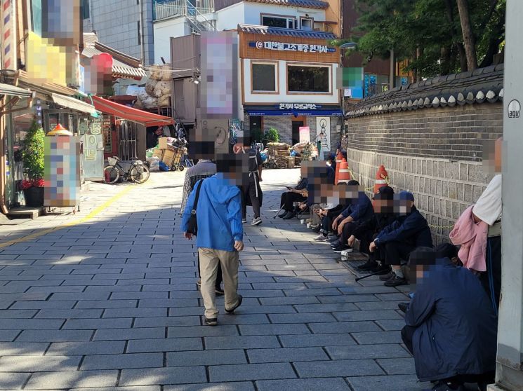 지난 15일 서울 종로구 탑골공원 담벼락에 노인들이 모여 앉아 원각사 무료급식소의 배식을 기다리고 있다. 공병선 기자