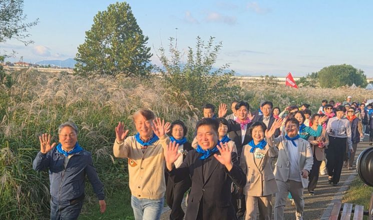 강기정 광주시장과 김이강 서구청장, 전승일 서구의회 의장 등을 비롯한 참석자들이 시민들과 함께 억새밭 길을 걸으며 손을 흔들고 있다. 송보현 기자