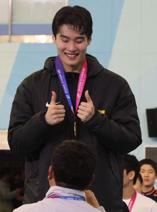 황선우가 20일 오후 부산 사직실내수영장에서 열린 제106회 전국체육대회 수영 남자 일반부 자유형 200m 결승 시상식에서 금메달을 목에 걸고 기뻐하고 있다.    [사진 제공= 연합뉴스]