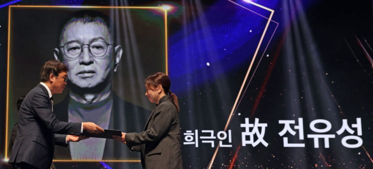 최휘영 문화체육관광부 장관이 23일 서울 중구 국립극장 해오름극장에서 열린 대한민국 대중문화예술상 시상식에서 희극인 고(故) 전유성 씨에게 수여된 옥관문화훈장을 그의 딸 전제비 씨에게 대신 전달하고 있다.