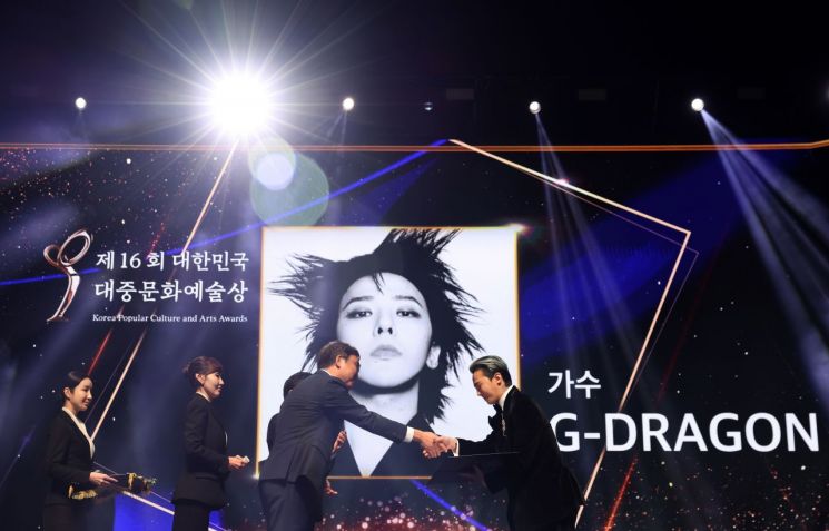 최휘영 문화체육관광부 장관이 23일 서울 중구 국립극장 해오름극장에서 열린 ‘대한민국 대중문화예술상’ 시상식에서 가수 지드래곤에게 옥관문화훈장을 전달하고 있다.
