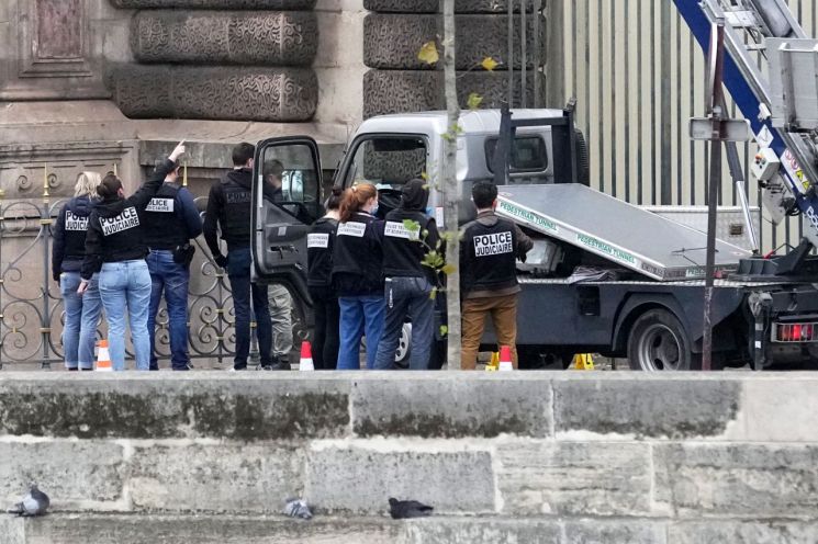 지난달 19일 프랑스 파리 루브르 박물관에서 경찰관들이 절도범들이 사용한 고가 작업차 옆에서 조사 작업을 하고 있는 모습. AP연합뉴스