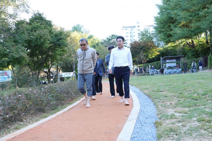 계룡시가 금암수변공원에 맨발길을 개장했다. 이응우 시장(오른쪼)이 시민들과 맨발길을 체험을 하고 있다/계룡시