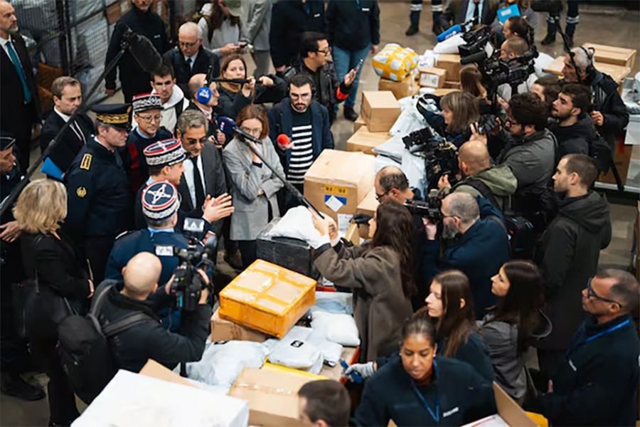 11월 6일 프랑스 루아시 샤를 드골 공항 물류 창고에서 하얀 장갑을 착용한 세관 직원들이 쌓여 있는 ‘쉬인’발(發) 소포를 열어 보는 가운데, 세르주 파팽 중소기업부 장관과 아멜리에 드몽샬랭 공공회계부 장관 등 정부 인사와 취재진이 이들을 둘러싸고 지켜보고 있다. 세관 관계자는 소포 20만개를 열고 위법 물건을 가려내는 데 최소 한 달이 걸릴 것이라고 말했다. /ABACAPRESS