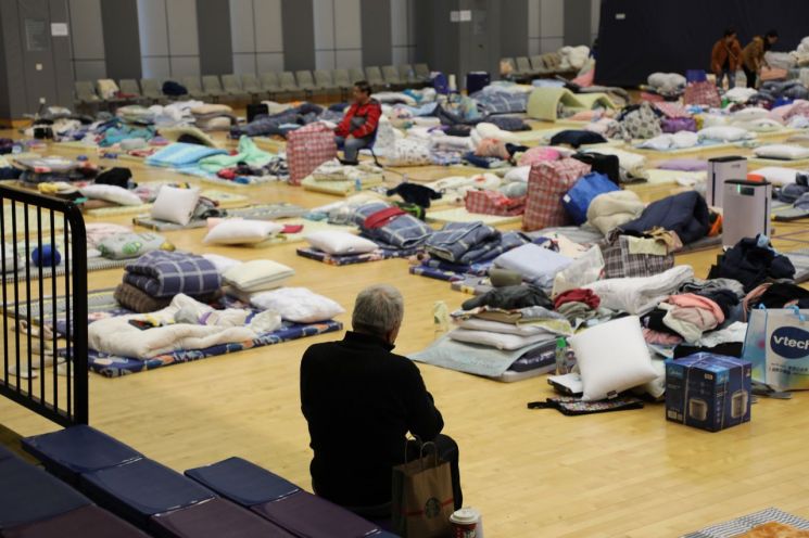 28일(현지시간) 임시 대피소가 마련된 홍콩 북부 퉁 청 거리 시민회관 강당에 화재 피해자가 앉아서 쉬는 모습. 연합뉴스