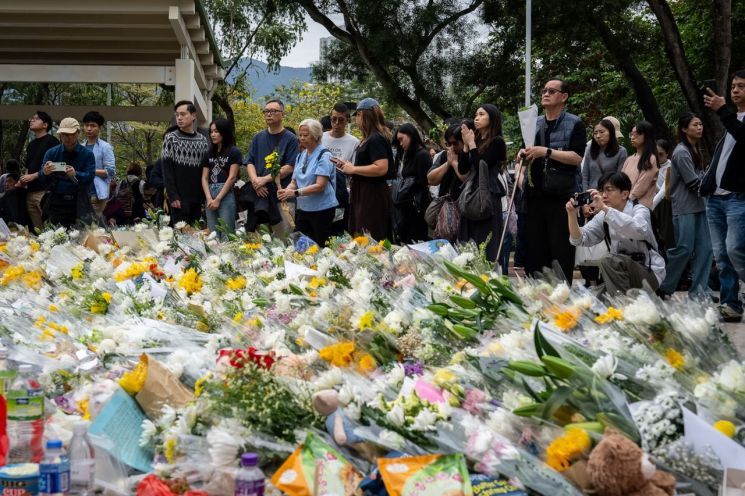 30일(현지시간) 홍콩 신계 타이포 지구 인근 화재 현장 근처에서 사람들이 꽃을 바치며 희생자들을 위해 기도하는 모습. AP연합뉴스
