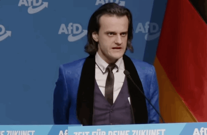 파란 연미복을 입고 연단에 선 그는 히틀러처럼 혀를 거세게 굴리는 에르(r) 발음을 구사하며 검지를 휘두르며 연설했다. 유튜브 채널 'AfD TV'