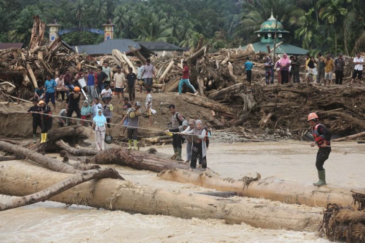 People are crossing the river using logs in Batangtoru, North Sumatra, Indonesia. Photo by AP Yonhap News