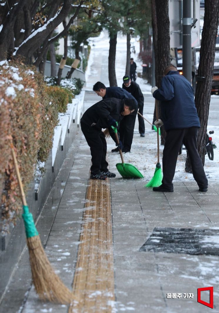 On the 5th, officials of a building in Jung-gu, Seoul, are clearing snow from the sidewalks as the heavy snowfall from the previous day froze overnight due to subzero temperatures, causing many roads in downtown Seoul to ice over. 2025.12.05 Photo by Yoon Dongju
