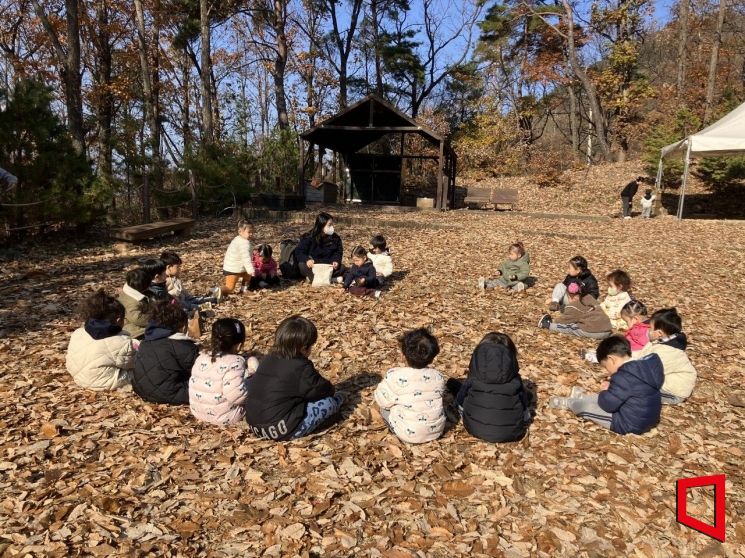 국립칠곡숲체원에서 영아들이 떨어진 낙엽을 손으로 만져보며 겨울 숲의 감촉과 소리를 탐색하는 활동에 참여하고 있다. /김이환 기자