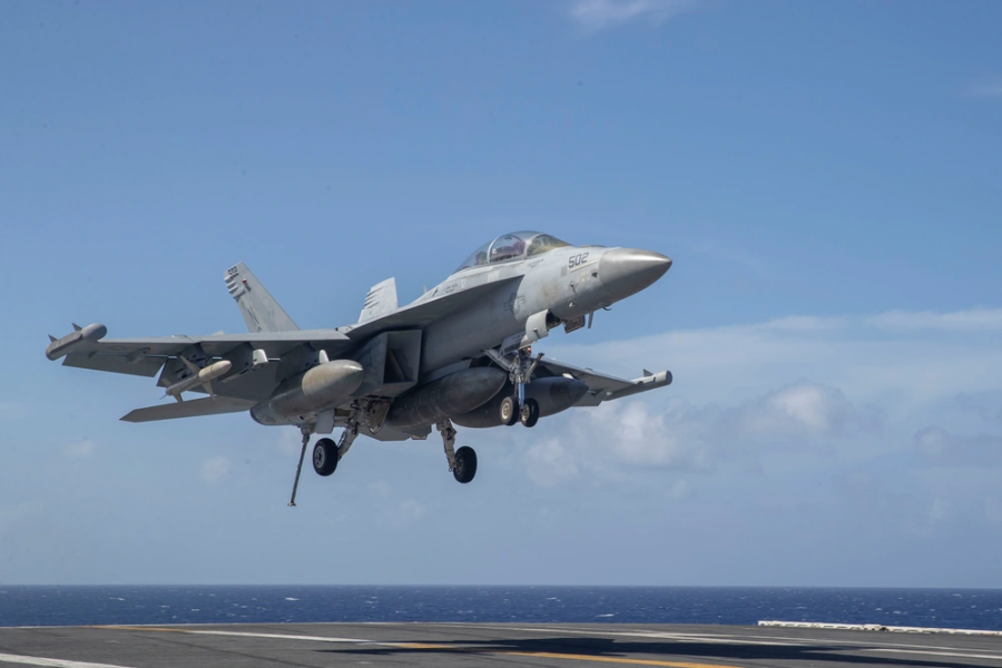 The US Navy's EA-18G Growler electronic warfare aircraft is preparing to land on the aircraft carrier flight deck. The Growler is tasked with jamming and neutralizing enemy air defense networks and communication systems.