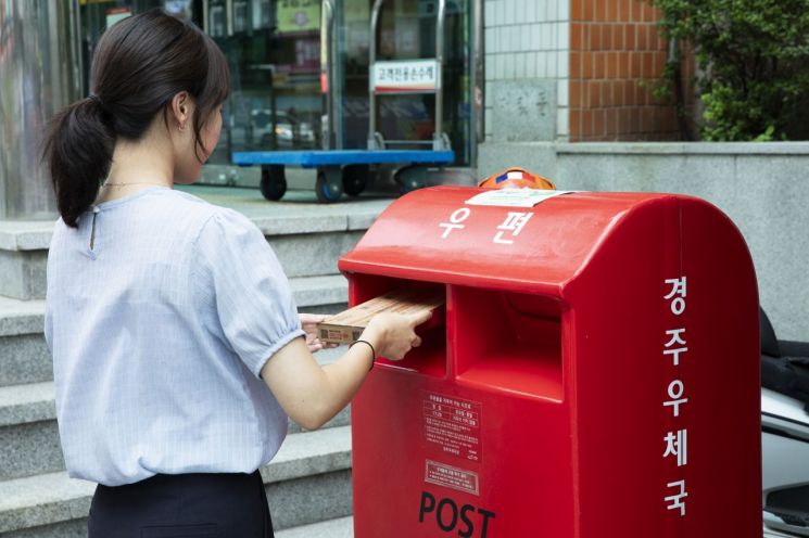고객이 우체국 소포 상자 '0호'를 우체통에 넣고 있다. 우정사업본부