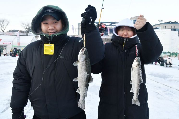 화천산천어축제장을 찾은 탐방객이 24일 낚시로 잡은 물고기를 들어 보이고 있다. 화천군 제공