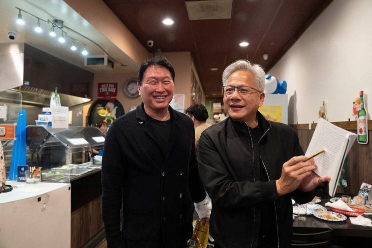 지난달 5일(현지시간) 미국 캘리포니아 산타클라라의 한국식 호프집 '99치킨'에서 가진 최태원 SK그룹 회장과의 만찬회동에서 젠슨 황 엔비디아 최고경영자가 신간 '슈퍼모멘텀'을 펼쳐보이고 있다. 연합뉴스.