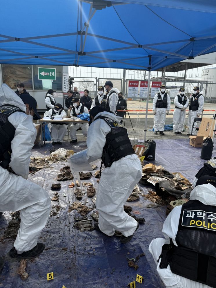 지난달 26일 무안국제공항 공항소방대 뒤편에서 항공철도사고조사위원회와 전남경찰청 과학수사대가 12·29 제주항공 참사 여객기 잔해를 조사하고 있다. 12·29 무안공항 제주항공 여객기 참사 유가족협의회 제공, 연합뉴스