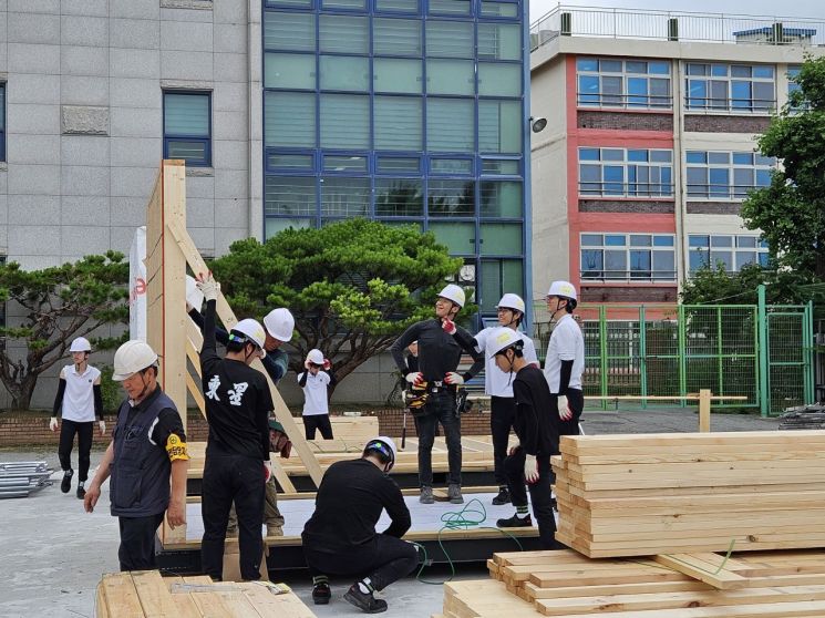 한국모빌리티고 학생들과 숙련 기능인들이 지난해 7월5일 학교 운동장에서 이동형 목조주택 벽체 골조를 함께 세우고 있다. 한국모빌리티고