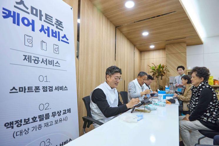 정재헌 SKT CEO가 어르신 고객의 스마트폰을 깨끗하게 닦고 있다.