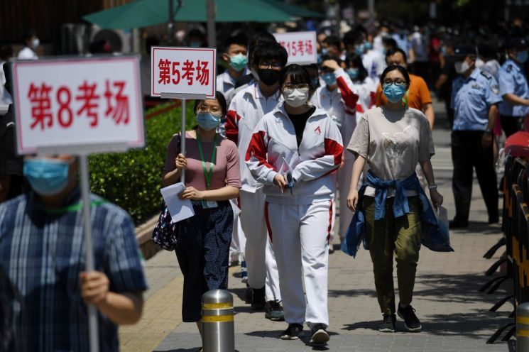 Students who took the Chinese university entrance exam known as 'Gaokao' are leaving an exam site in Beijing under the guidance of teachers and administrative staff. Photo by AFP Yonhap News