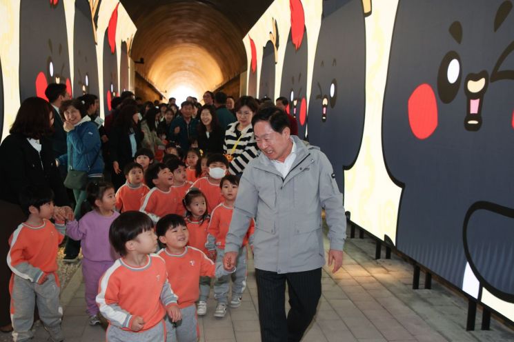 Ju Gwangdeok南杨州市长31日在Wabu邑Dogok里一带举行利用废弃隧道打造的“光影隧道公园”竣工仪式后，正与儿童一起步行。南杨州市提供