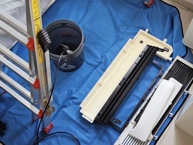 지난 25일 LG전자의 휘센 시스템 에어컨 세척을 위해 분리한 내부 부품과 불순물 배출을 위해 외부로 연결된 관의 모습. 박준이 기자.