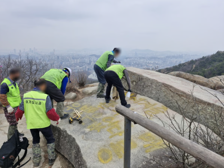 冠岳区厅休闲城市科工作人员正在修复被涂鸦破坏的岩石。冠岳区厅提供