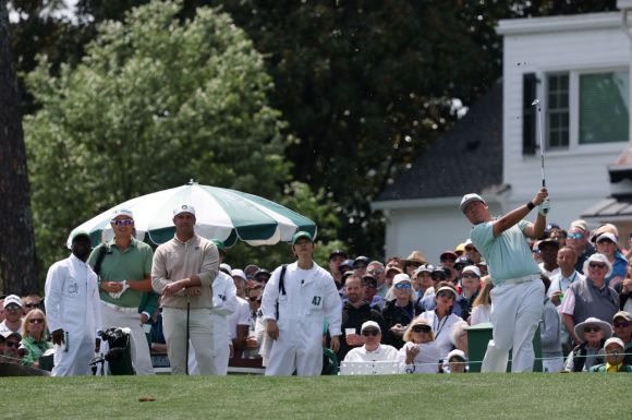 임성재가 마스터스 파3 콘테스트에서 티샷을 하고 배우 송중기가 캐디백을 메고 지켜보는 모습