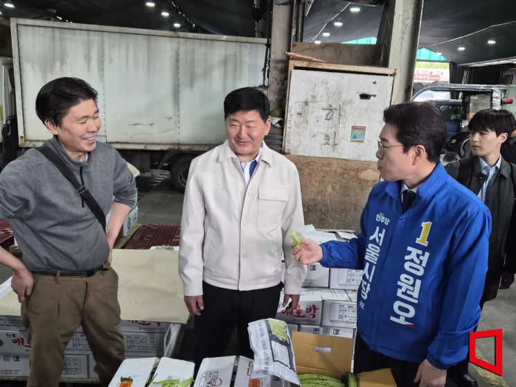 정원오 더불어민주당 서울시장 후보가 17일 오전 7시30분께 서울 가락농수산물종합도매시장에서 상인이 건넨 오이를 시식하며 대화하고 있다. 심성아 기자