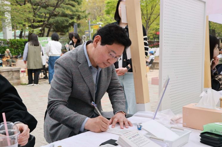 이상일 용인특례시장이 17일 수지구 신정공원 독서광장에서 열린 ‘제2회 공원 리딩 파티’ 체험 부스에서 '자신의 인생 책'을 시민과 공유하고 있다. 용인시 제공