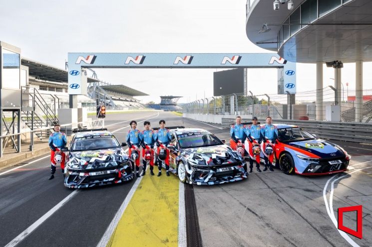 뉘르부르크링 서킷에서 경주차 엘란트라 N1 RP(왼쪽 첫째, 둘째)와 엘란트라 N TCR을 배경으로 드라이버들이 기념촬영하고 있다. 왼쪽부터 CJ 세풀베다, 김규민, 신우진, 김영찬, 마크 바쎙, 미켈 아즈코나, 니코 바스티안. 현대차