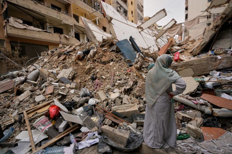 On April 17, 2026, residents walk past the debris of buildings destroyed after the ceasefire between Israel and Hezbollah in Dahieh, southern suburbs of Beirut, Lebanon. (left) On April 20, 2026, a woman stands next to the debris of buildings destroyed after the ceasefire between Hezbollah and Israel in Dahieh, southern suburbs of Beirut, Lebanon. Photo by AP Yonhap News