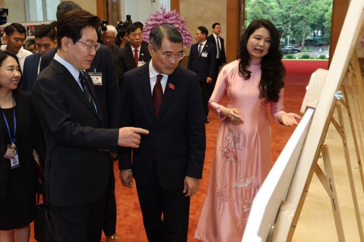 President Jae-myung Lee, on a state visit to Vietnam, is viewing a photo related to South Korea and Vietnam with Prime Minister Le Minh Hung at the Hanoi Prime Minister's Office on the 23rd (local time). Photo by Yonhap News Agency